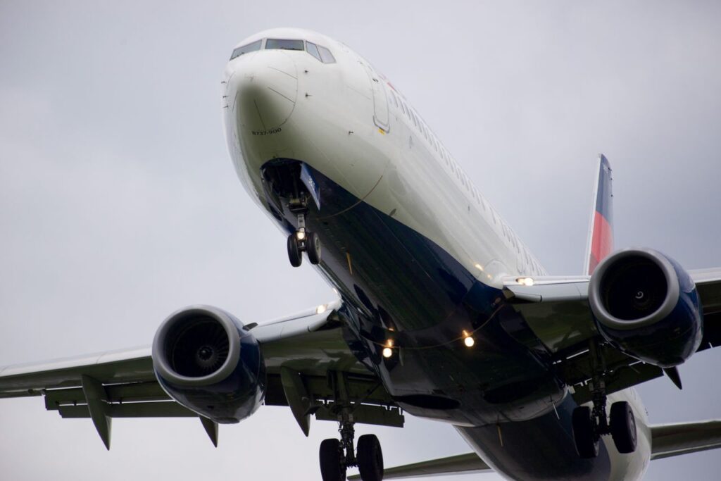Close-up, low-angle shot of an airplane in flight against a cloudy sky.